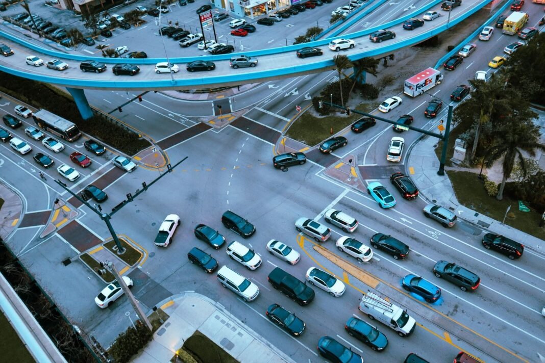 Aerial view of a busy urban intersection filled with traffic under an overpass.
